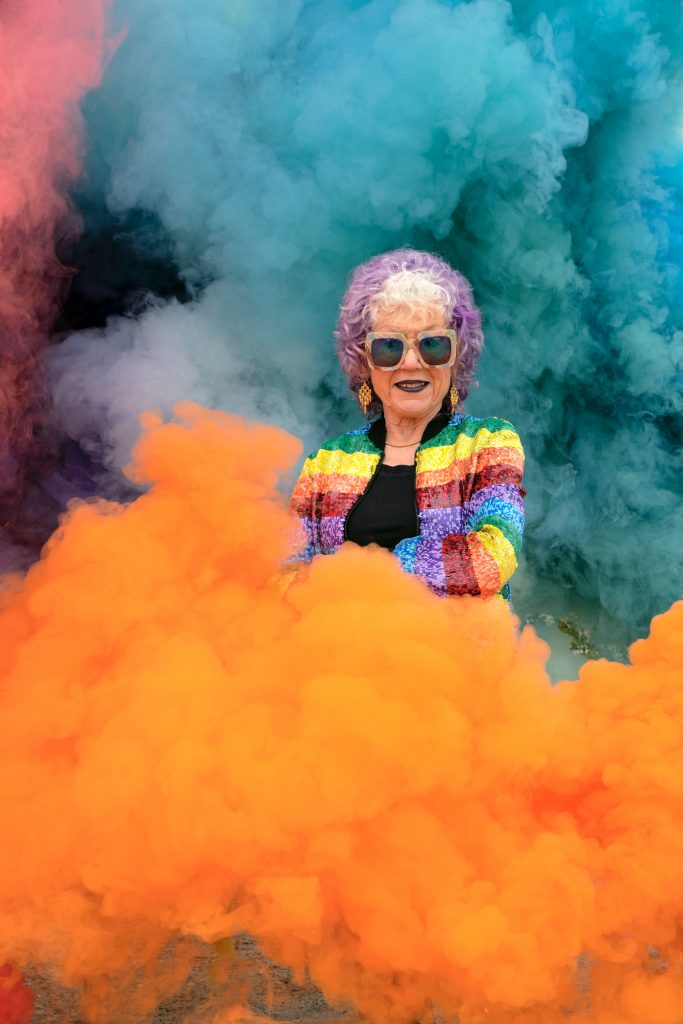 Judy Chicago stands in her rainbow smoke art